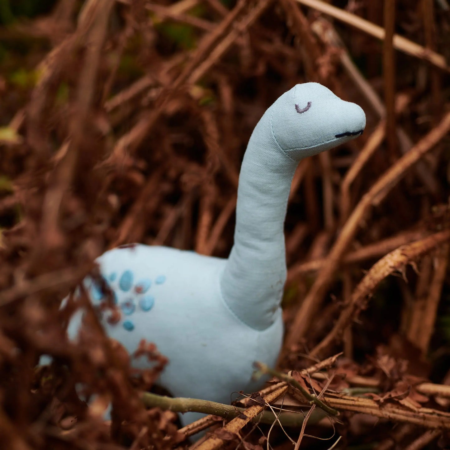 Plush toy dinosaur among dry leaves