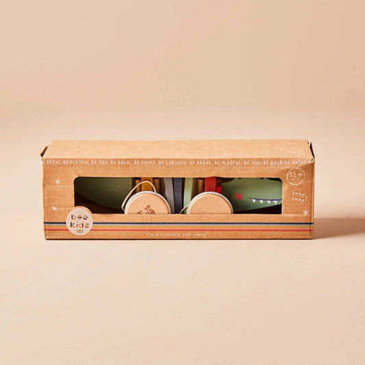 Packaged children's crocodile toy with a clear window on a beige background