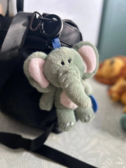 Plush elephant keychain attached to a bag with a blurred background