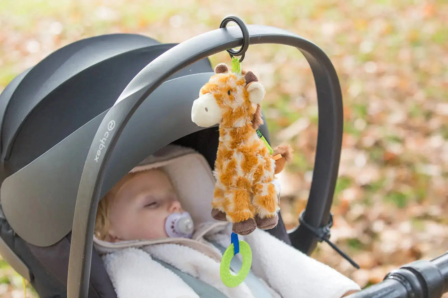 Baby in a buggy with a giraffe toy hanging from the canopy