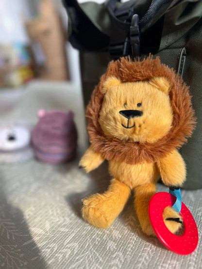 Plush lion toy with a red teether attached to a bag.