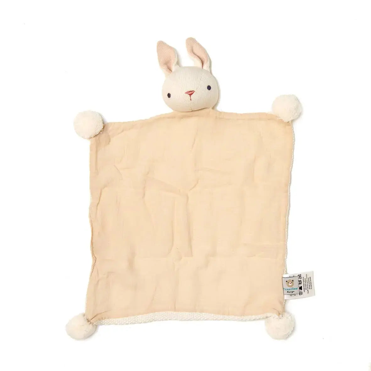 Beige blanket with bunny head and pom-pom ears on a white background
