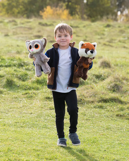 Child holding two plush toys in a grassy field