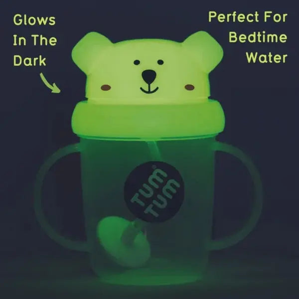 Glowing green sippy cup with polar bear design and 'Tum Tum' branding on a dark background.