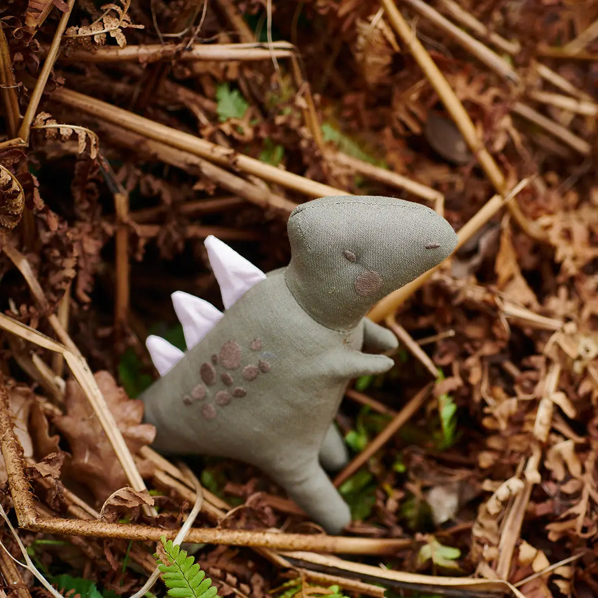 Toy dinosaur on a bed of dry leaves and twigs