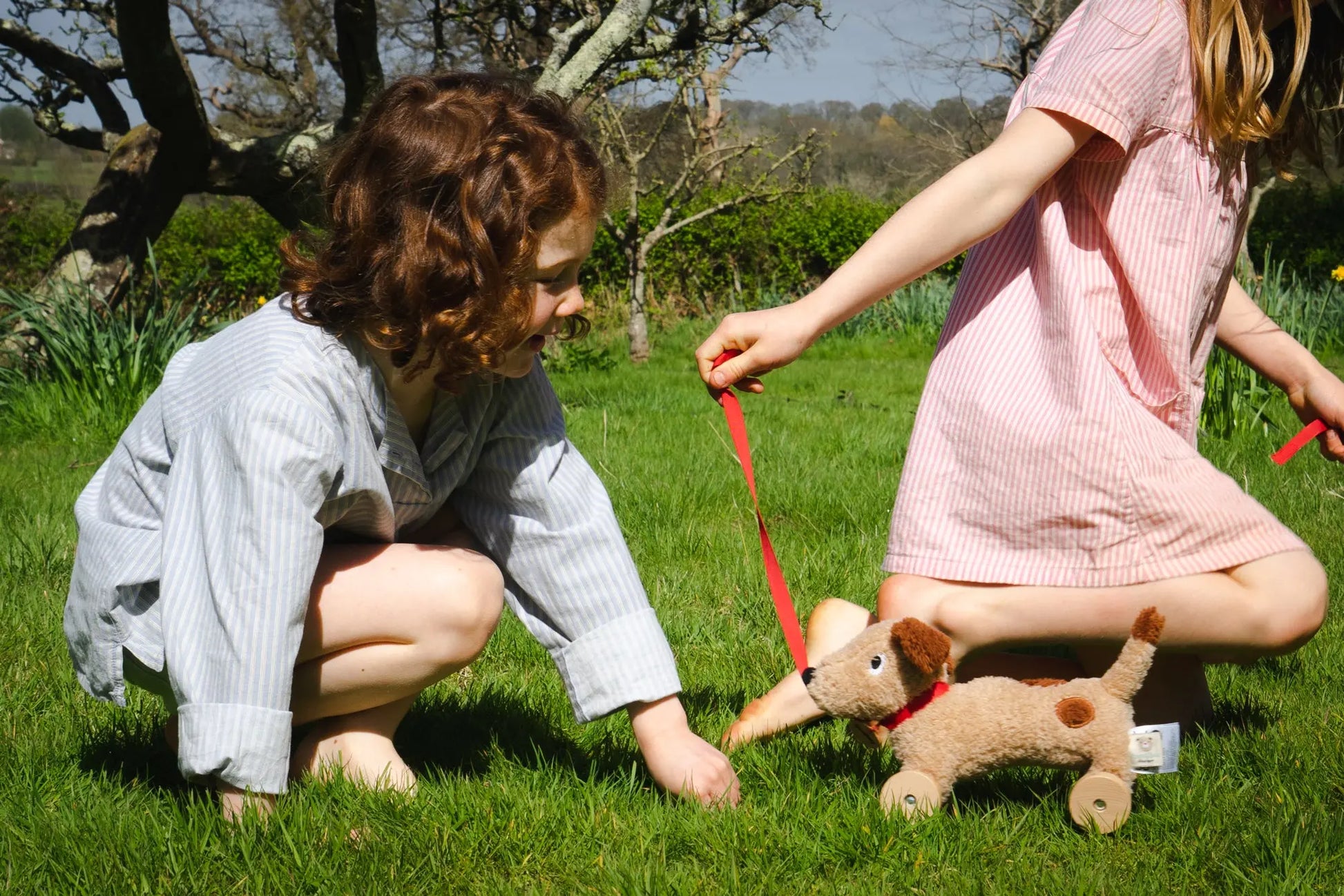 Two kids with a plush dog toy on a grassy field