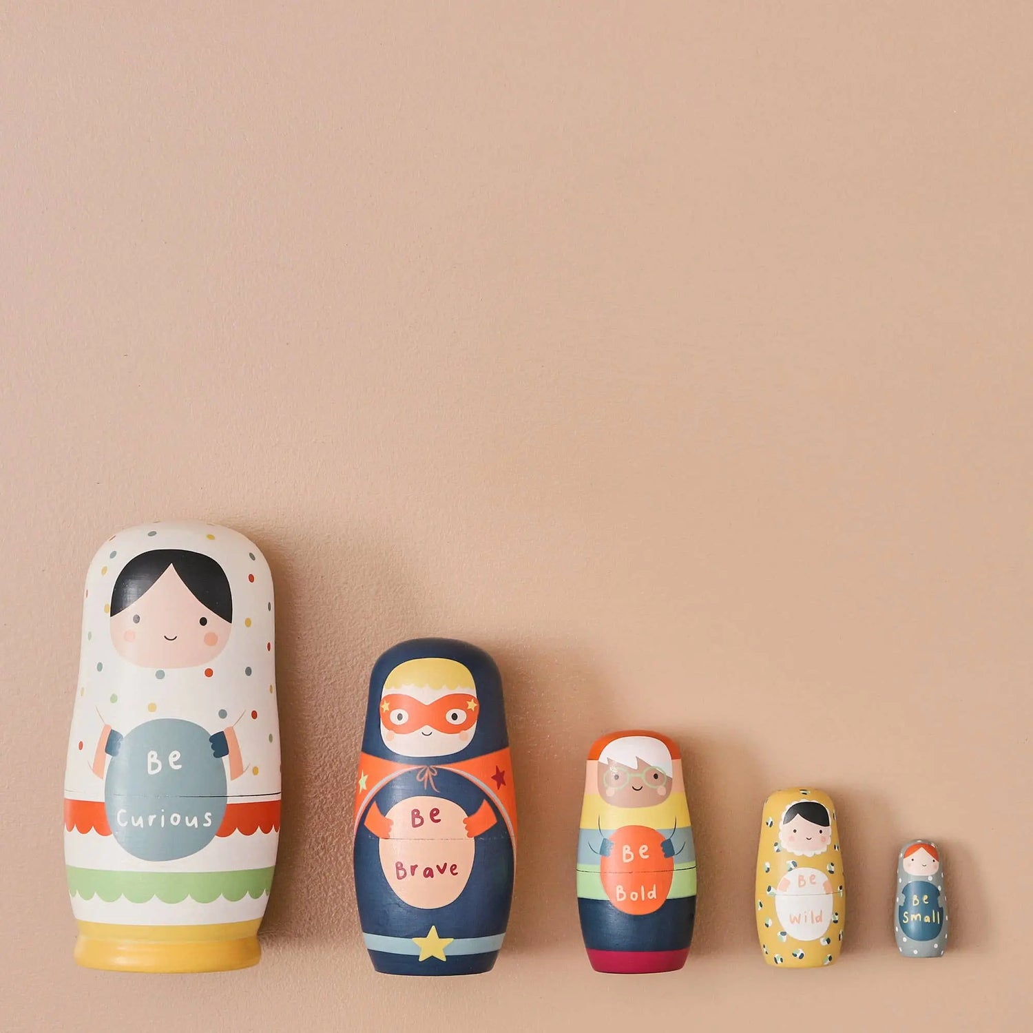 Set of colourful wooden nesting dolls with motivational phrases on a beige background