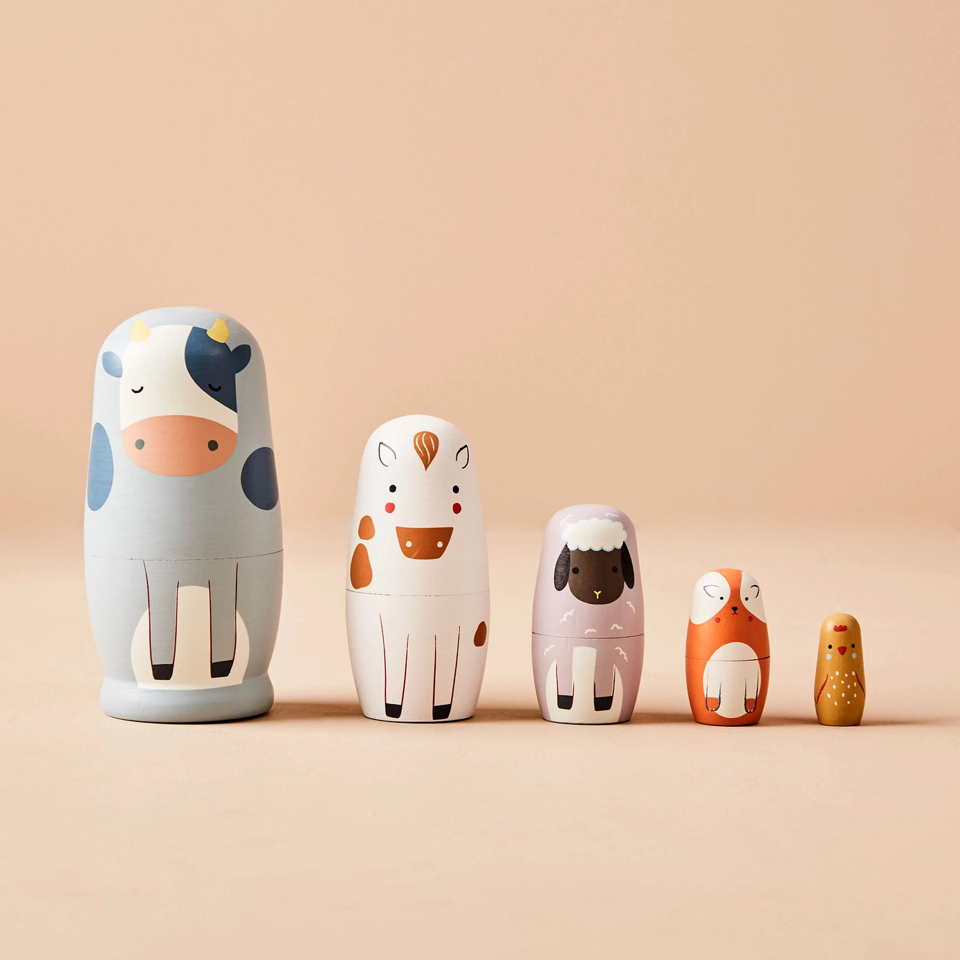 Set of five wooden nesting dolls with animal designs on a beige background