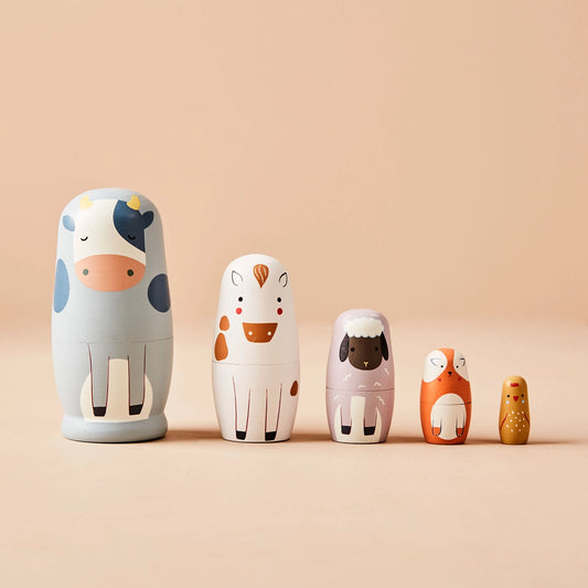 Set of five wooden nesting dolls with animal designs on a beige background