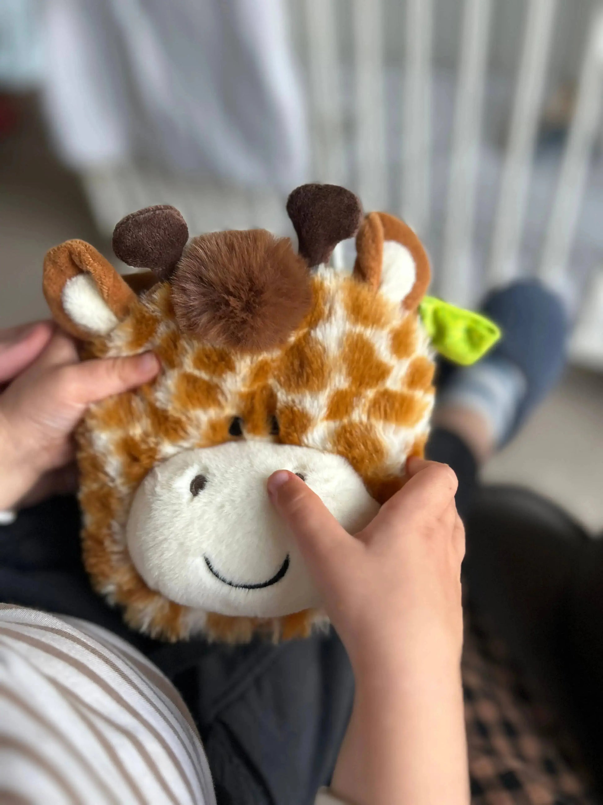 Plush giraffe puppet book toy held by a child with a blurred background
