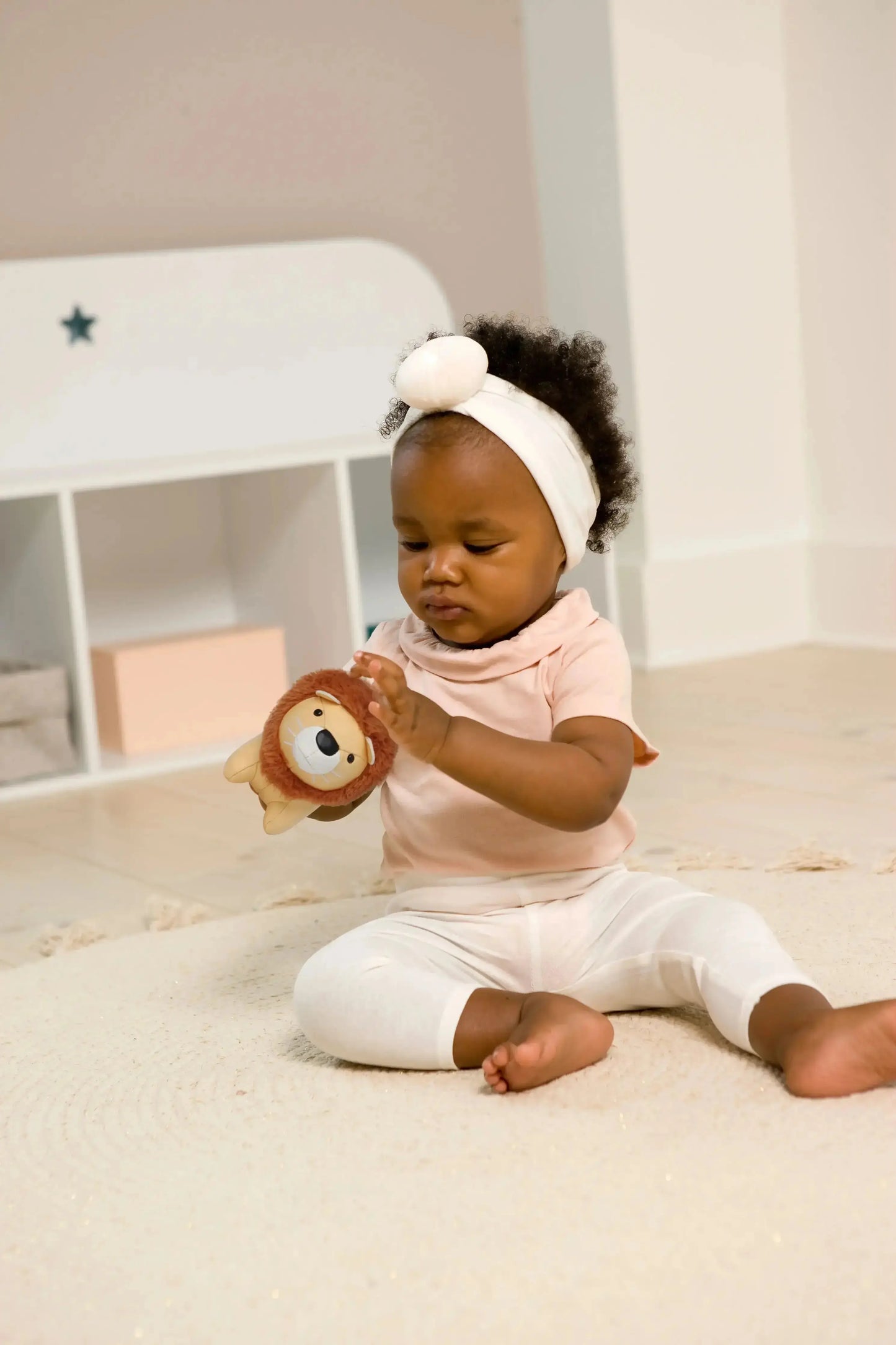 Baby playing with a lion toy in a crib