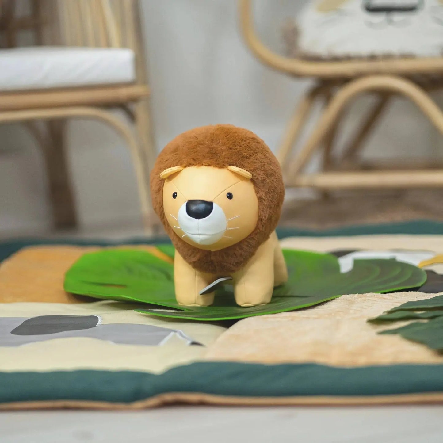 Plush lion toy on a colourful rug with a blurred background