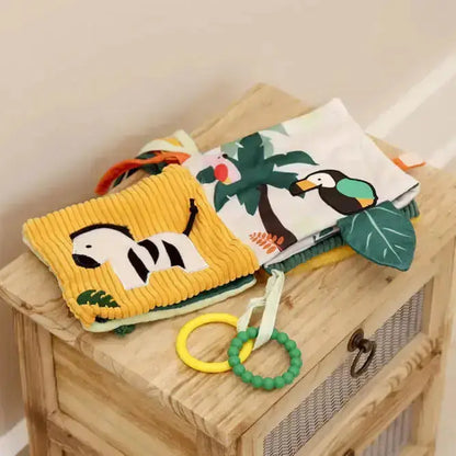 Soft baby book with animal illustrations on a wooden surface
