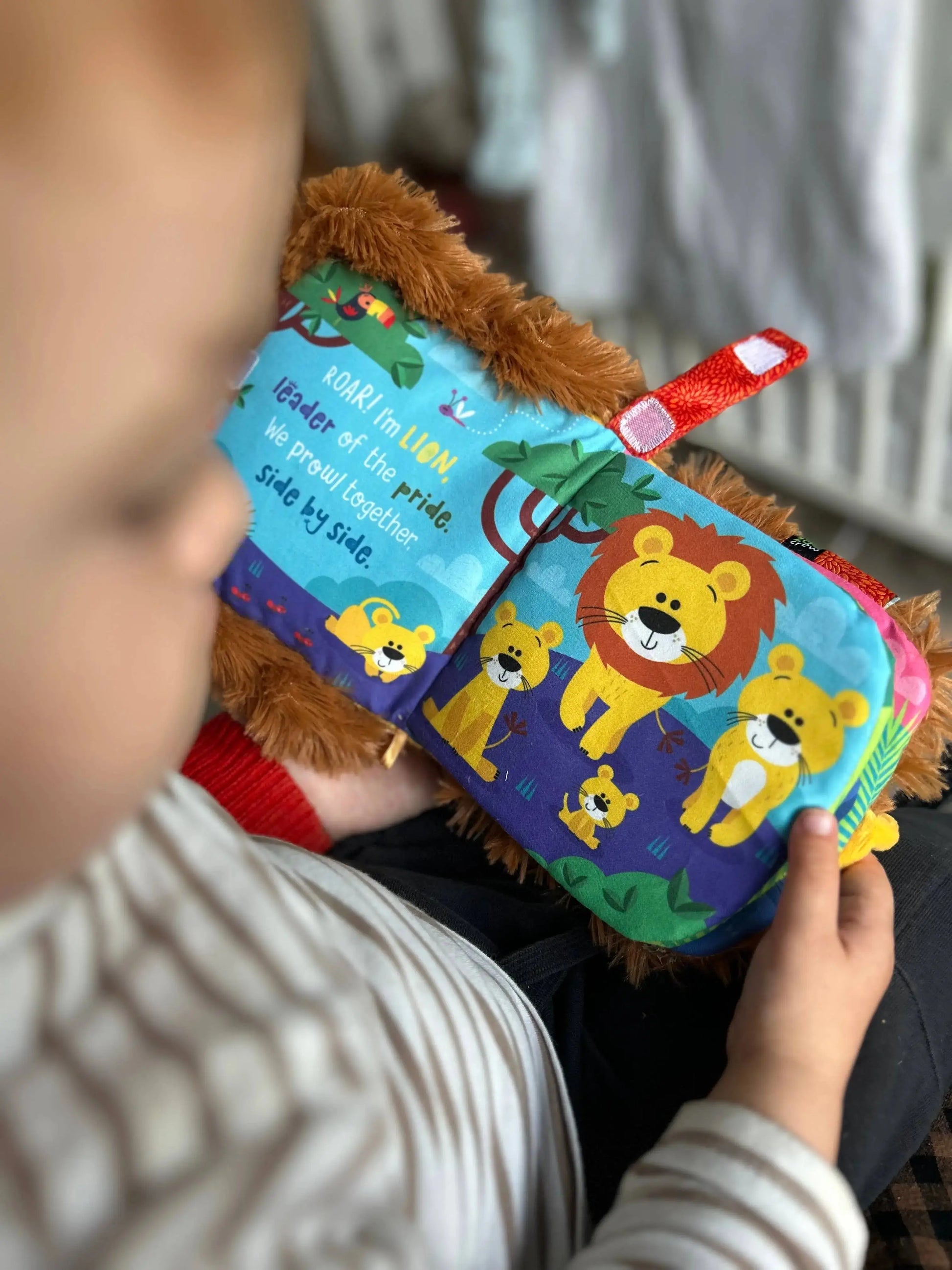 Child holding a soft book with lion illustrations