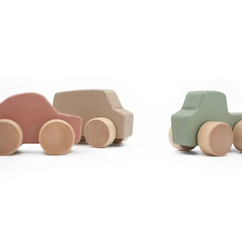 Three wooden toy cars in pastel colors on a white background