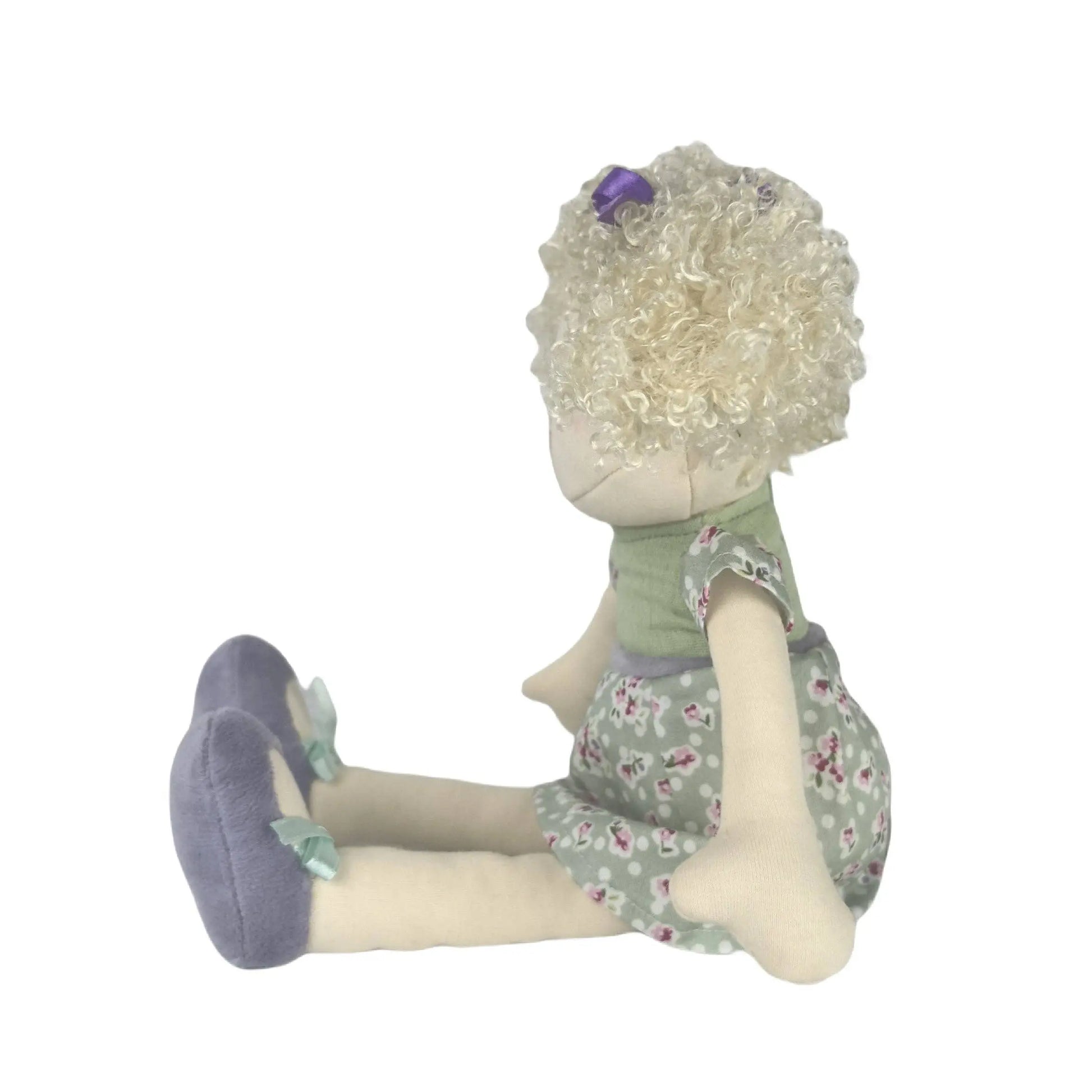 Stuffed toy with floral dress and purple shoes on a white background