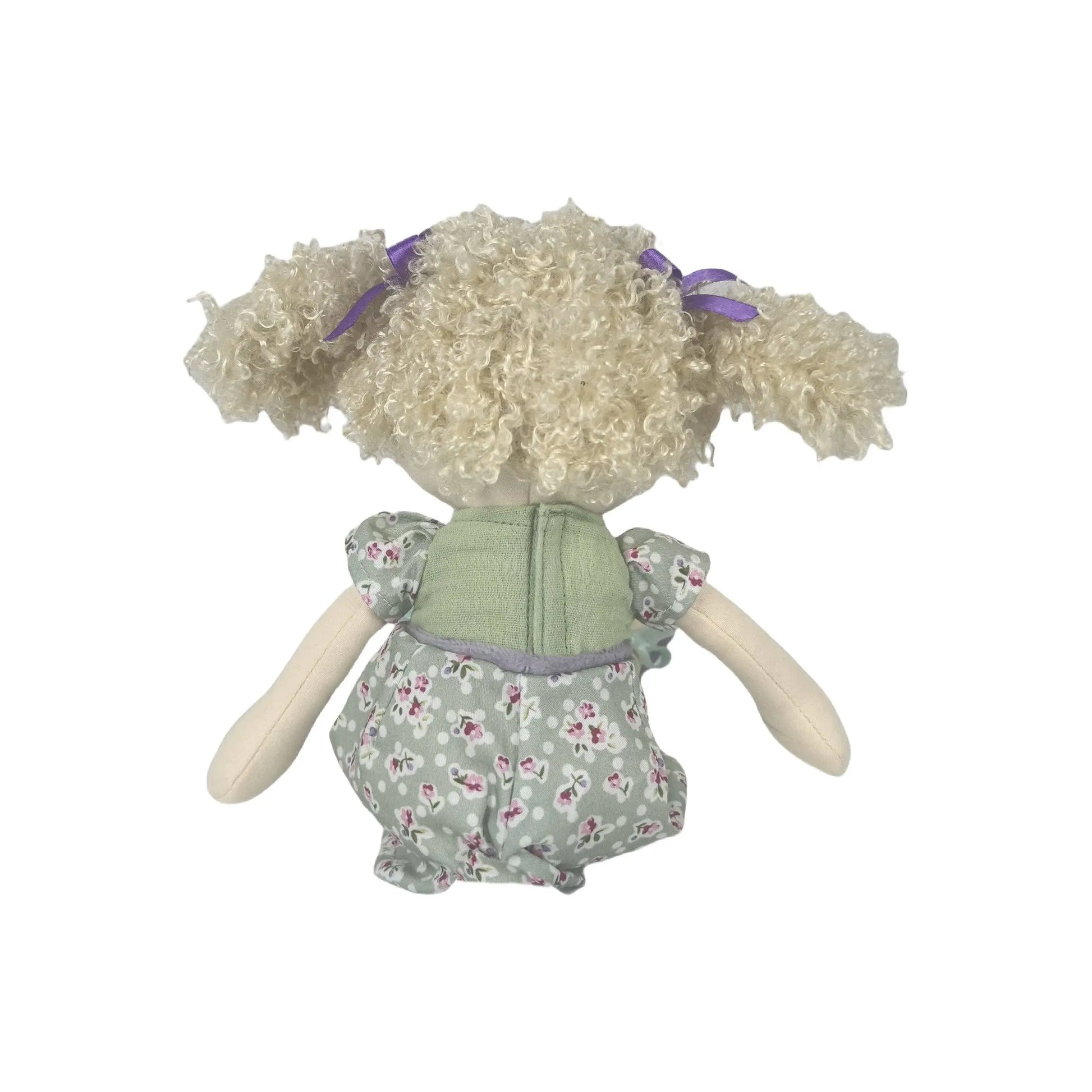 Toy doll with curly hair and a floral dress on a white background