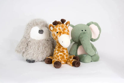 Three plush toys - a grey penguin, a giraffe, and a green elephant - on a white background.