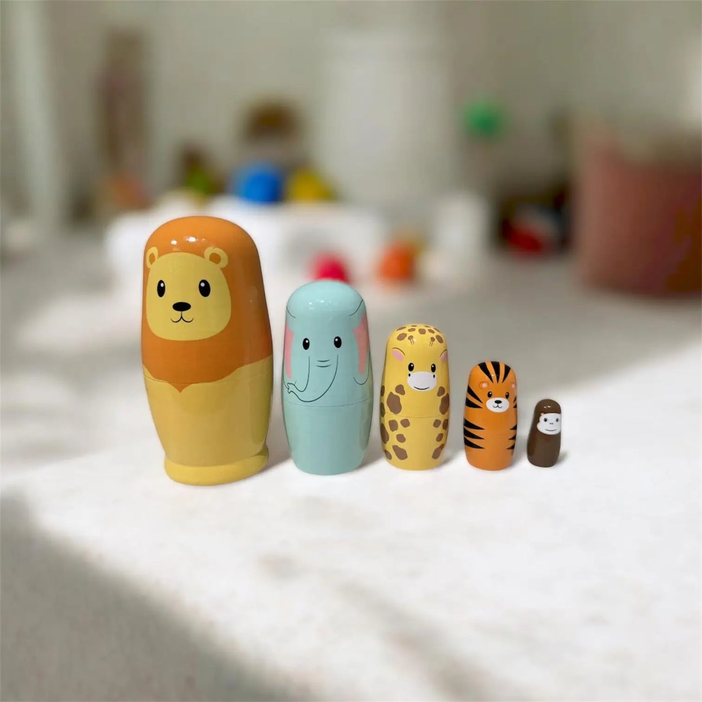 Set of colourful animal-themed nesting dolls on a white surface with a blurred background