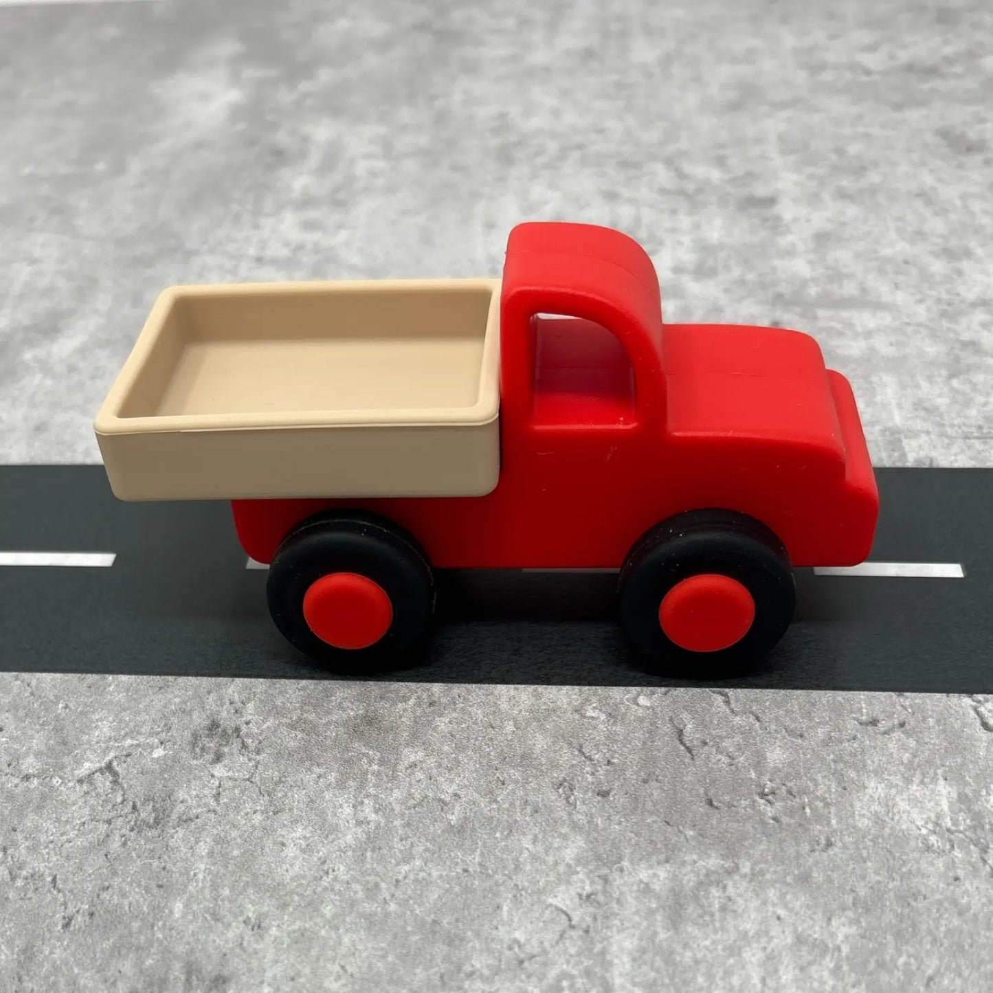 Red toy truck with beige bed on a grey surface