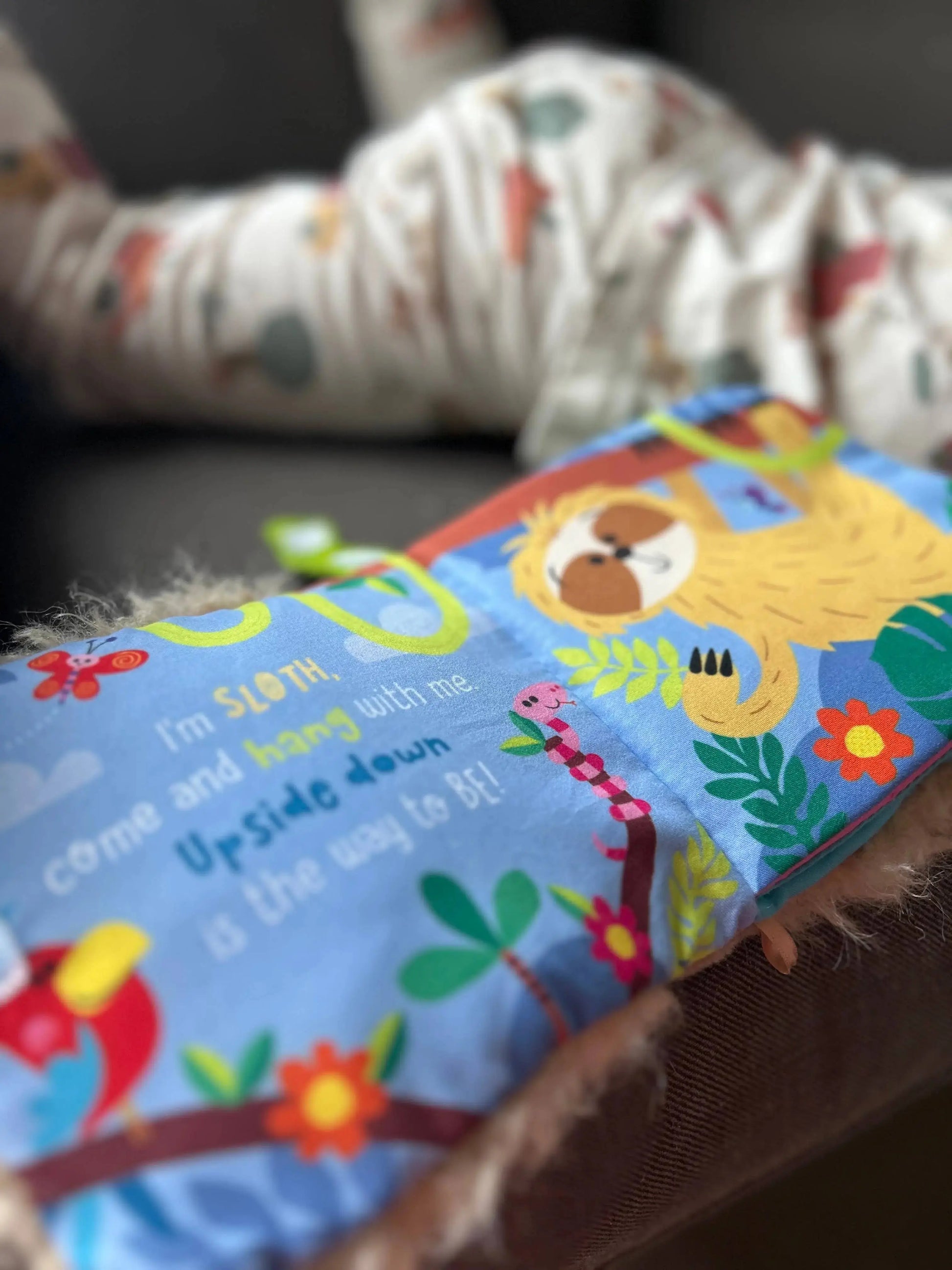Children's book with colourful sloth illustrations on a soft surface