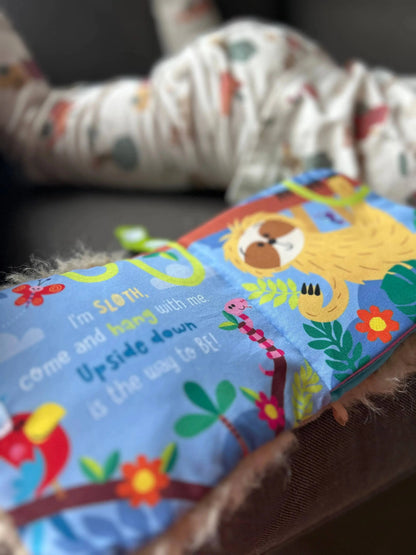 Children's book with colourful sloth illustrations on a soft surface
