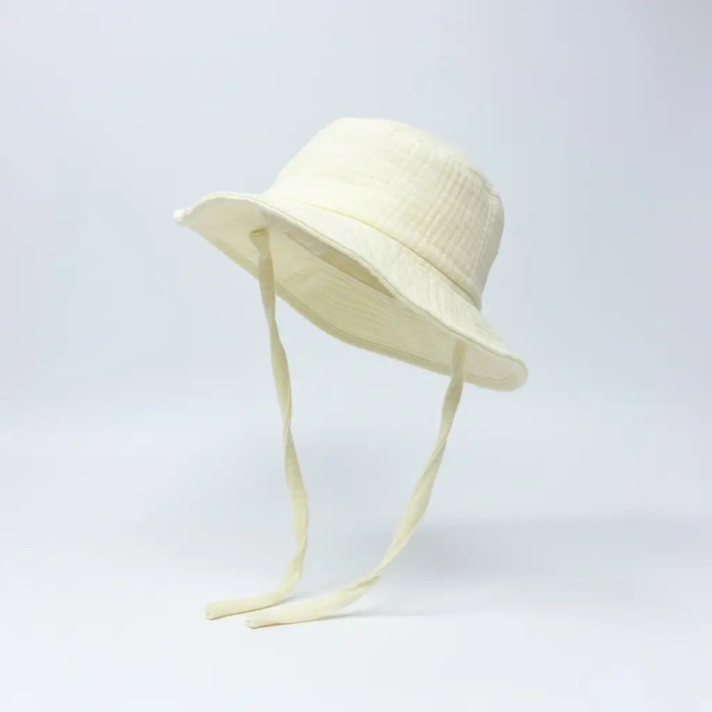 Lemon coloured baby hat with chin straps on a light grey background