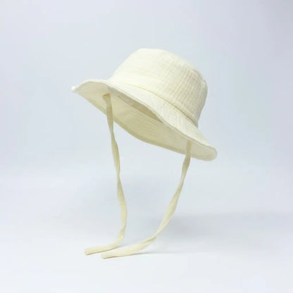Lemon coloured baby hat with chin straps on a light grey background