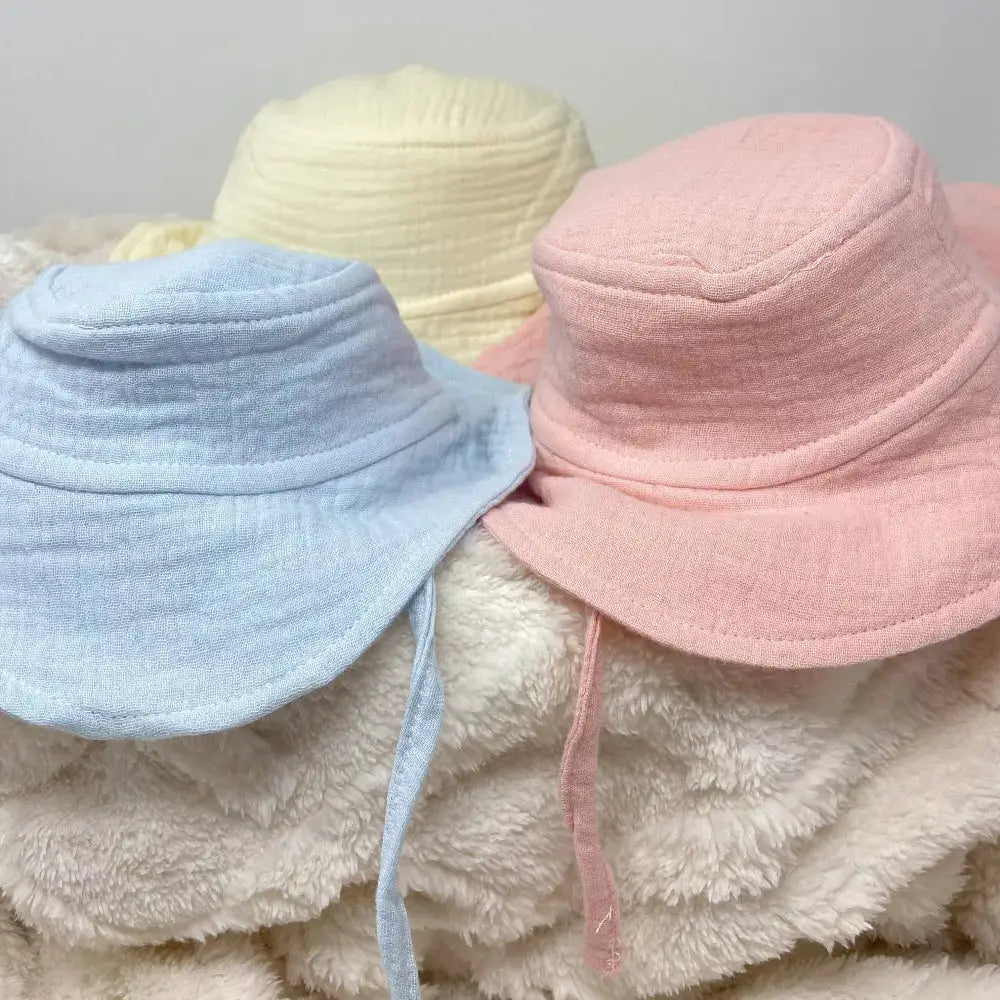 Three colourful bucket hats on a textured surface