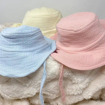 Three colourful bucket hats on a textured surface