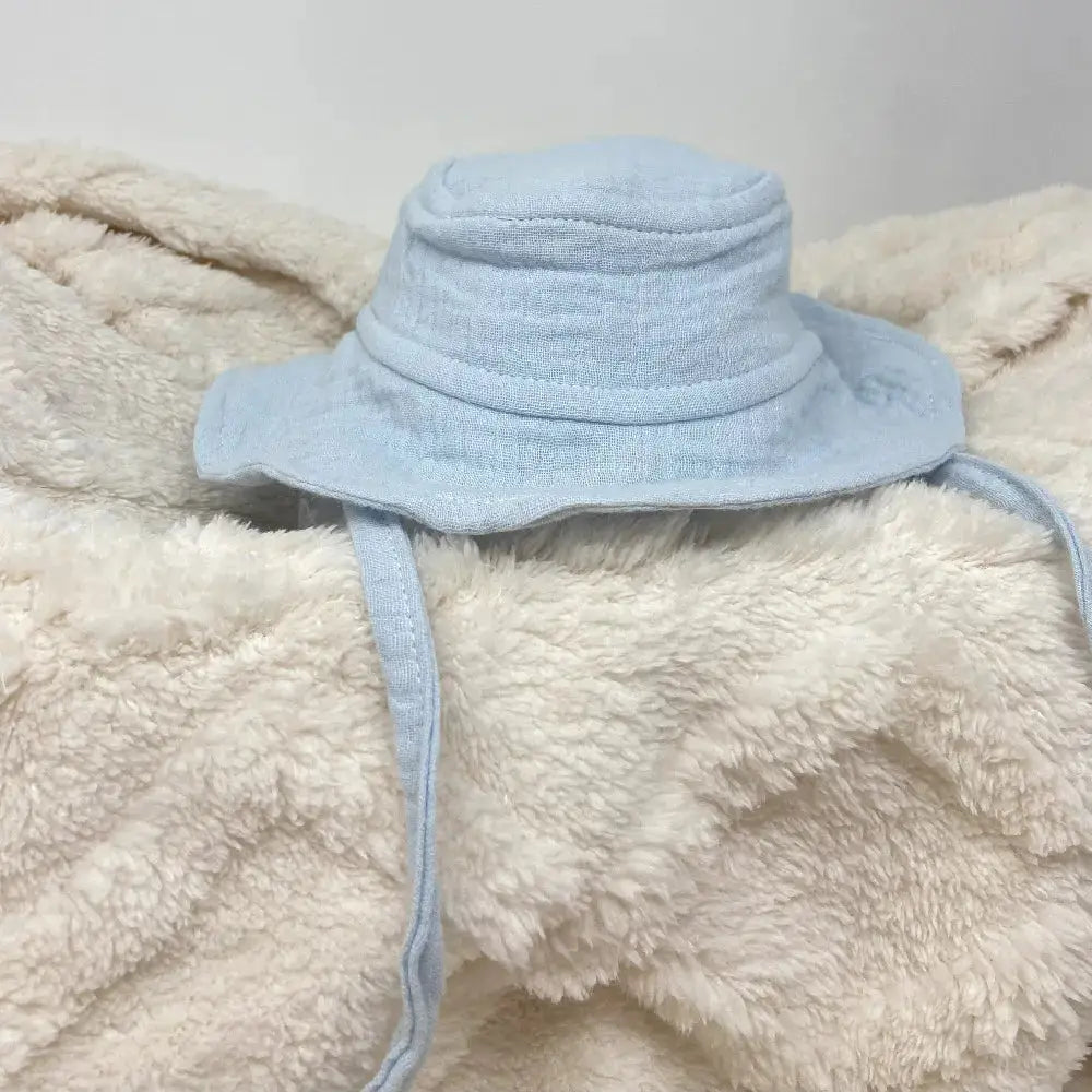 Light blue baby hat on a fluffy beige blanket