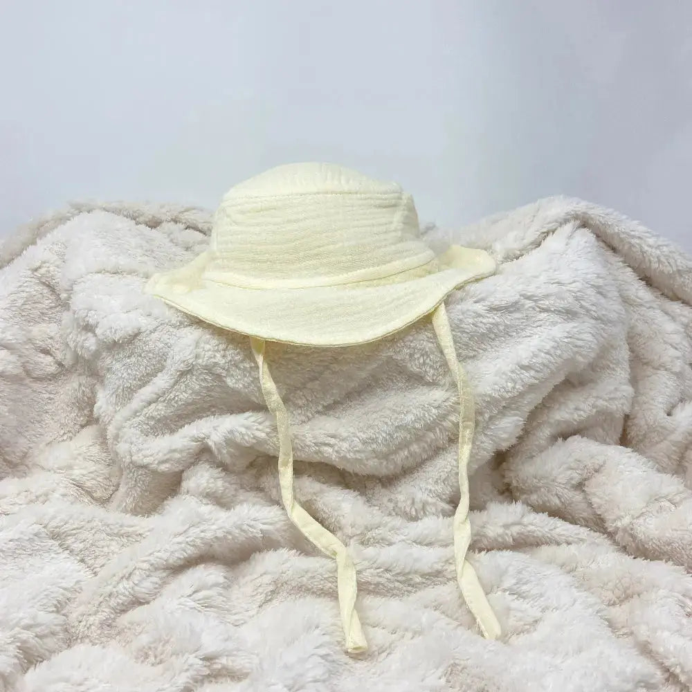 Light yellow sun hat on a fluffy white blanket