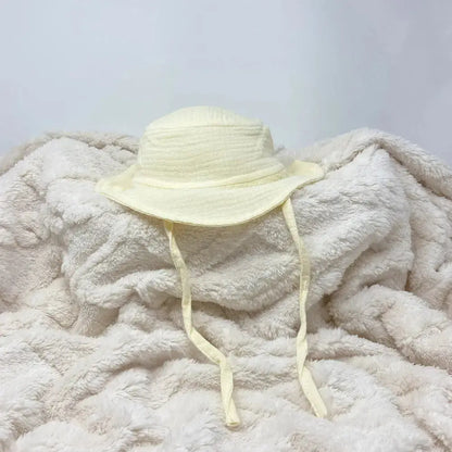 Light yellow sun hat on a fluffy white blanket