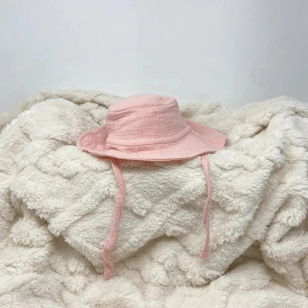 Pink sun hat on a fluffy white blanket