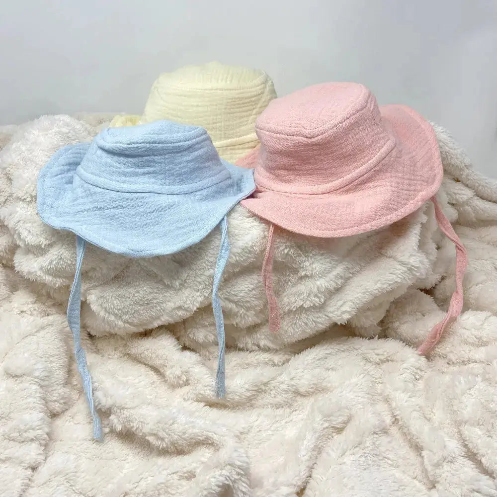 Baby sun hats on a cream fluffy blanket