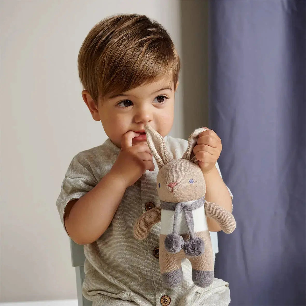 Child holding a plush toy in a neutral setting