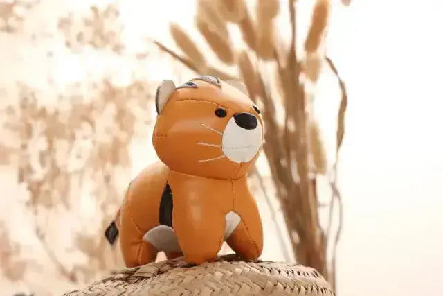 Plush toy tiger sitting on a woven surface with a blurred natural background