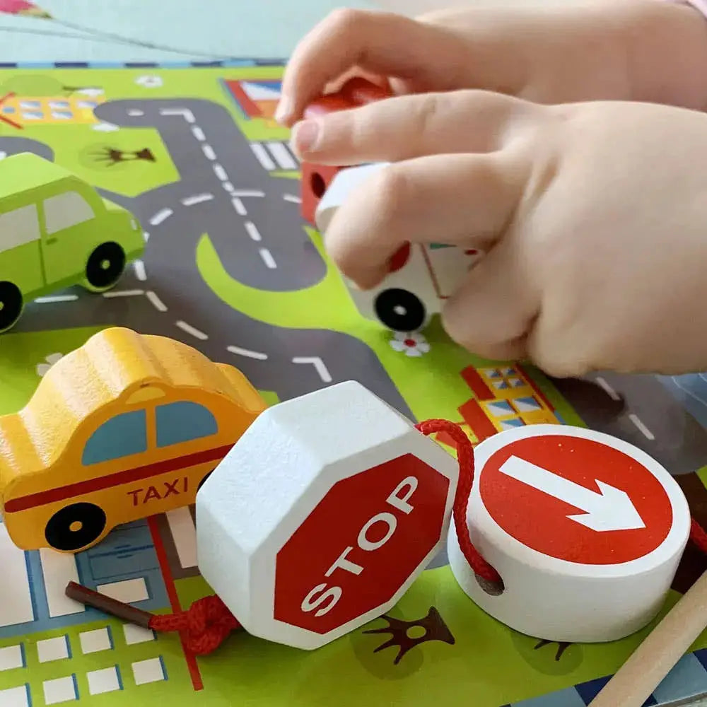 Child playing with toy traffic signs on a road map mat