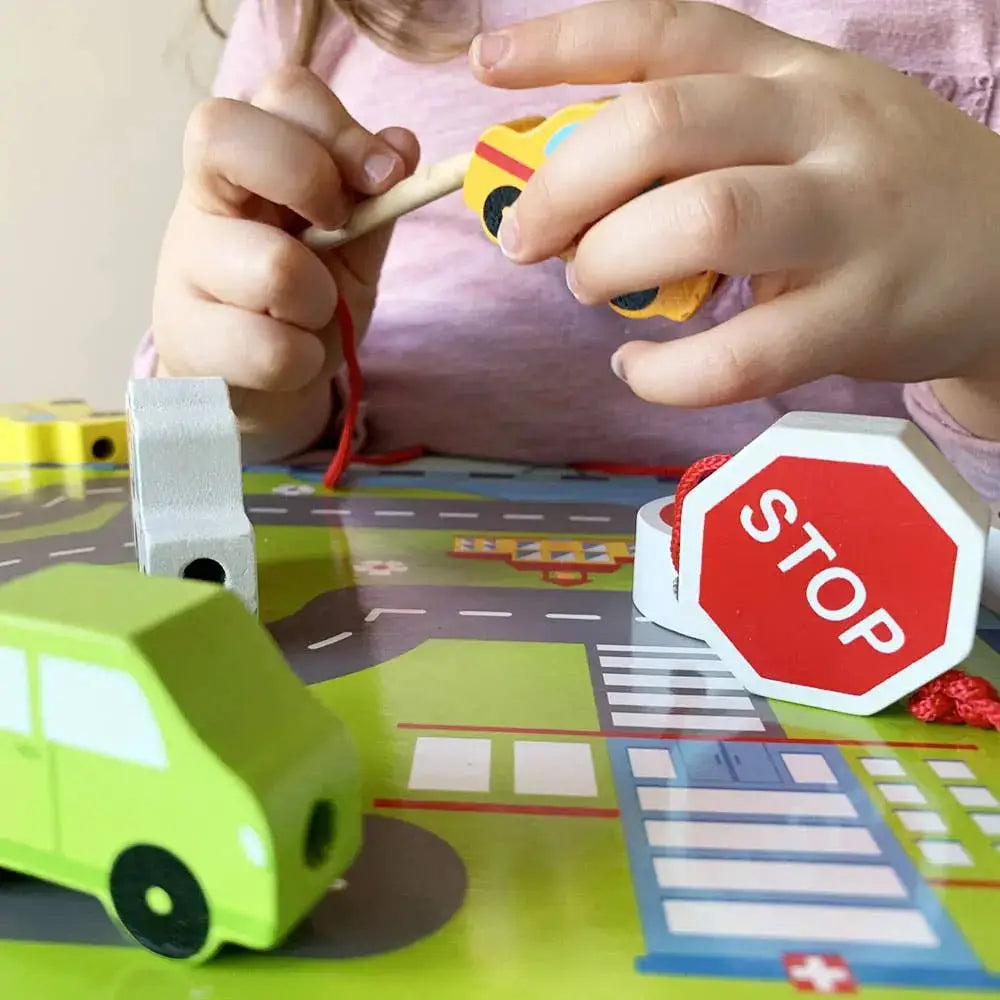 Children playing with toy cars and a stop sign on a road mat.