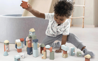 Child playing with colourful wooden blocks on a light-coloured floor.