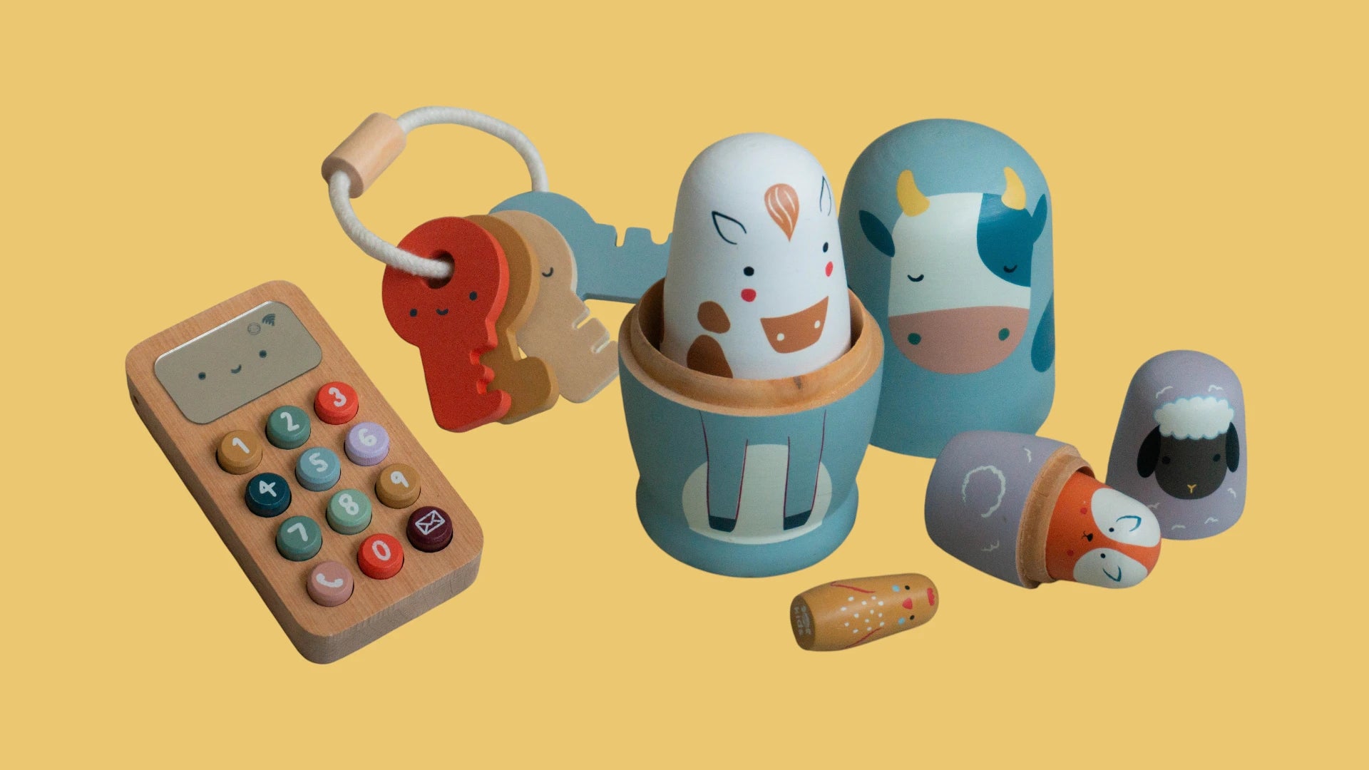 Set of wooden toys including a calculator, animal-shaped blocks, and nesting dolls on a yellow background